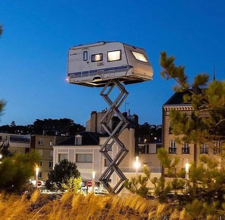 This meme features an image of a tiny house, known as a "treehouse," but it's actually a car with a house on top of it, perched on a giant metal pole, stuck in a tree. The text that appears in the image reads, "I've been trying to get out of a relationship, but I'm stuck in the tree with my ex."